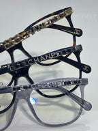 Chanel glasses close-up showing dark frames with gold chain-printed temple trim