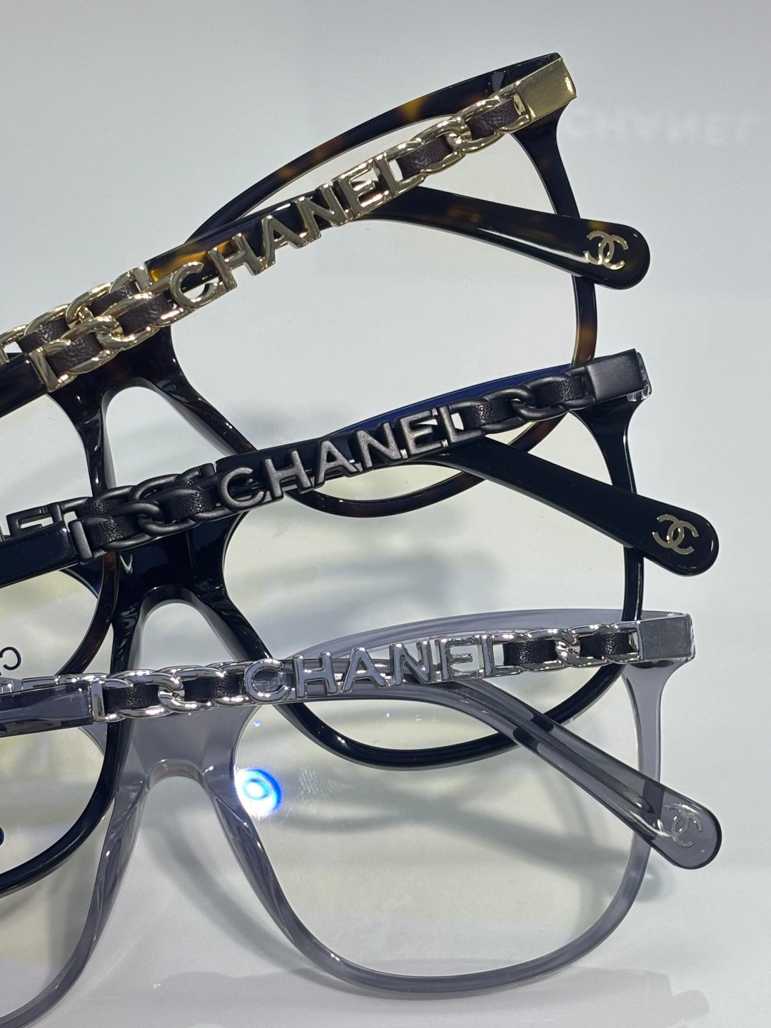 Chanel glasses close-up showing dark frames with gold chain-printed temple trim