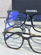 Overlapping dark eyeglasses with blue lenses and Chanel branding on rims