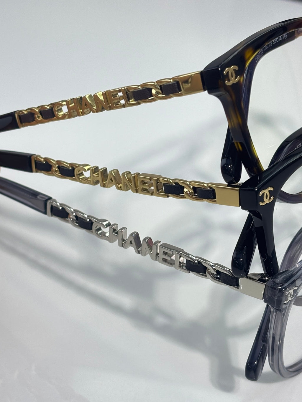 Chanel eyeglass frames close-up, gold chain links and CHANEL lettering on temple