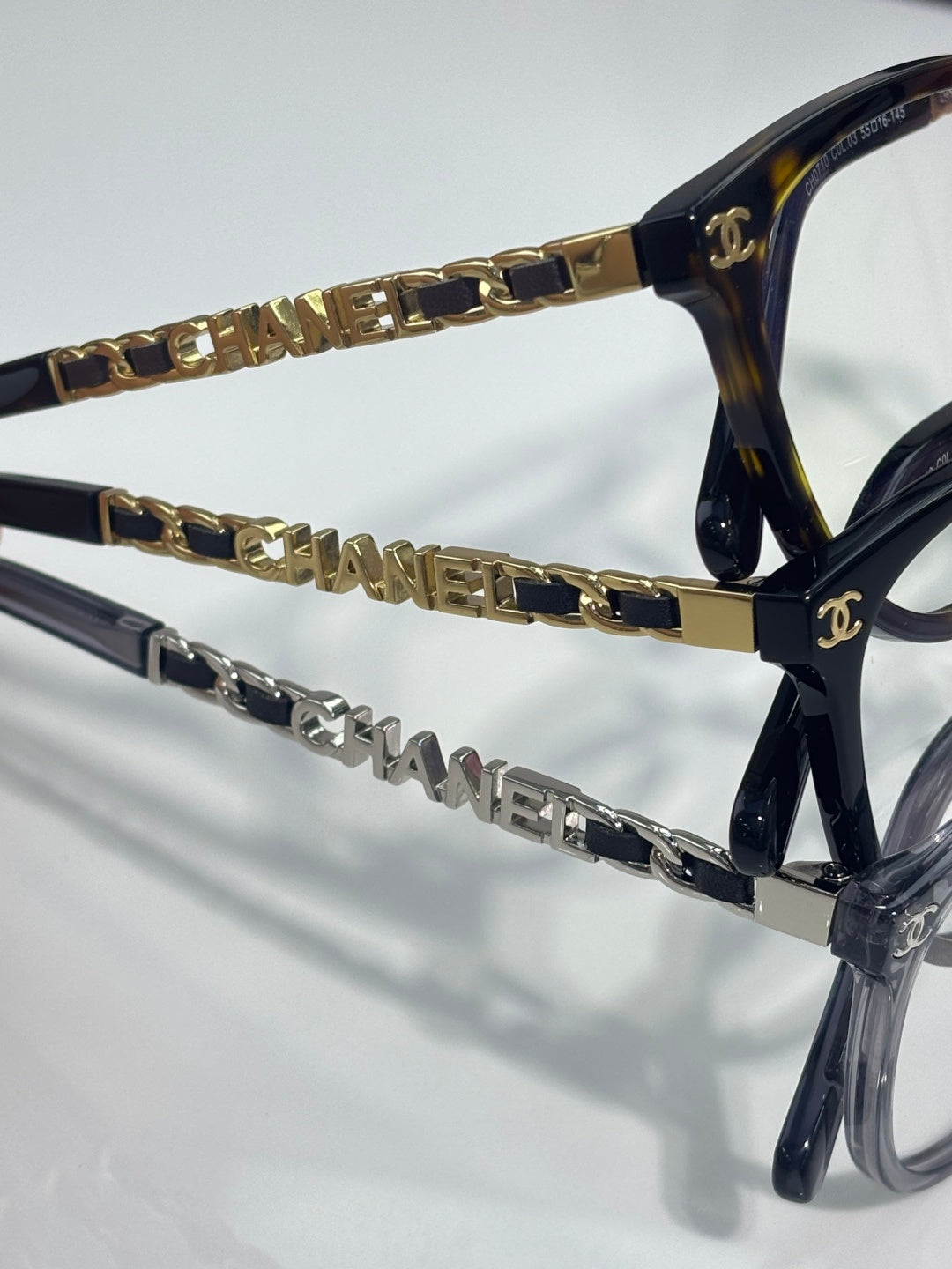 Chanel eyeglass frames close-up, gold chain links and CHANEL lettering on temple