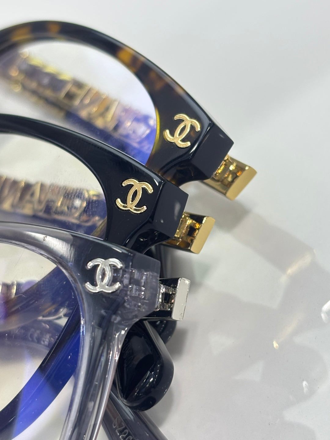 Chanel eyeglass frames close-up, hinge with gold CC logo and dark blue acetate