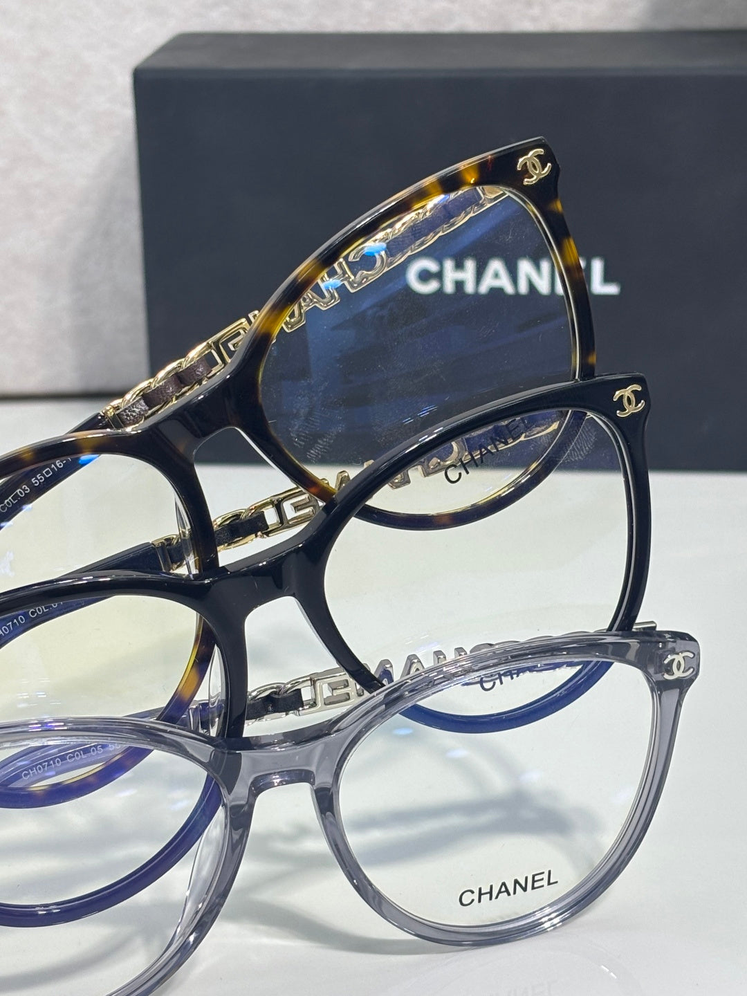 Chanel eyeglass frames stack view, dark blue round lenses with CHANEL script