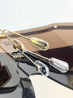 Gold-tone sunglasses hinge detail with tinted lens and engraved accents