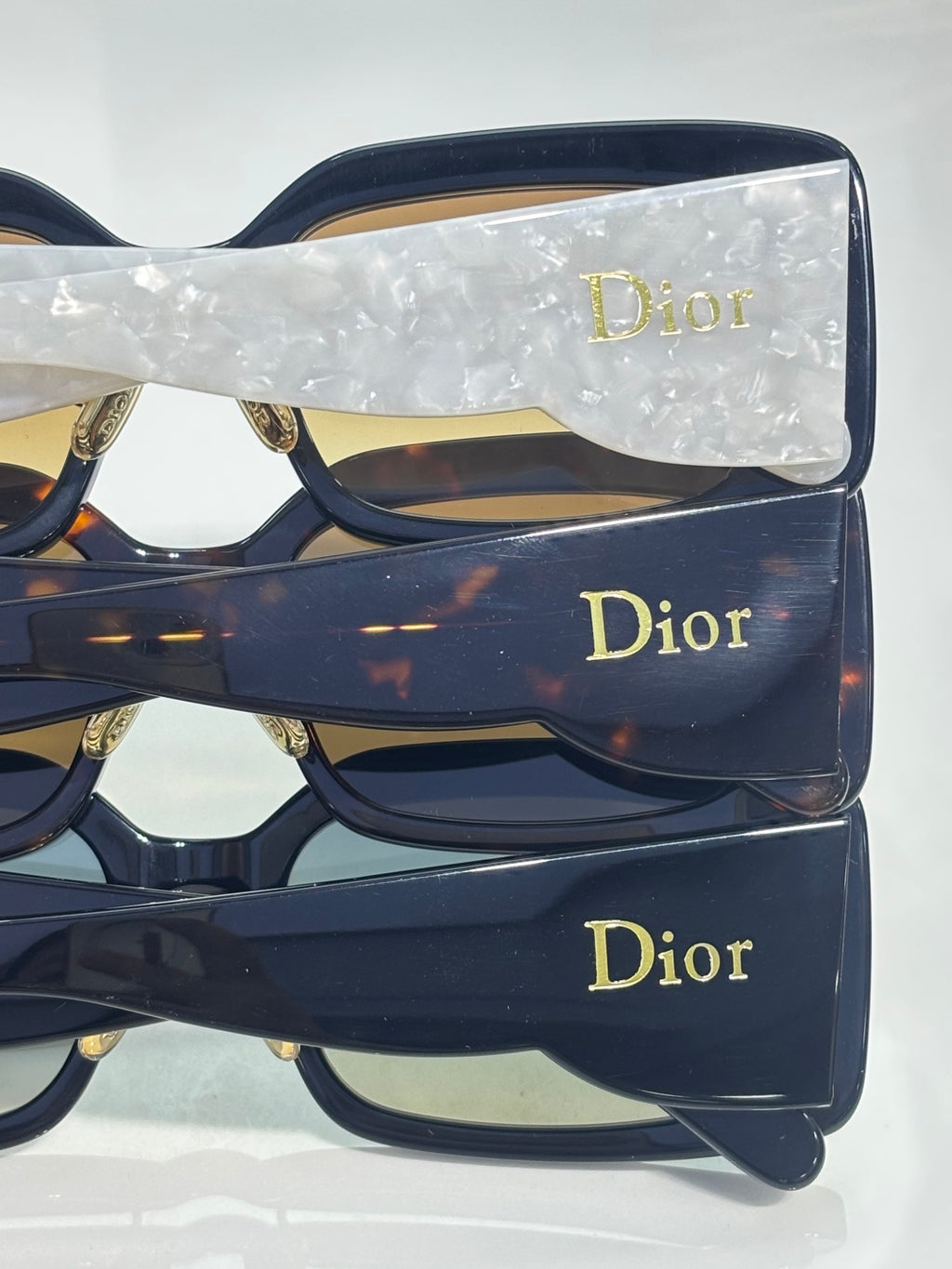 Dior sunglasses stacked with dark navy square frames and gold Dior logos