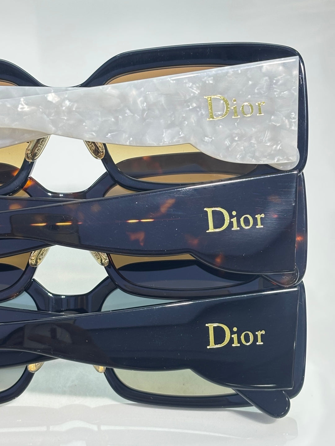 Dior sunglasses stacked with dark navy square frames and gold Dior logos