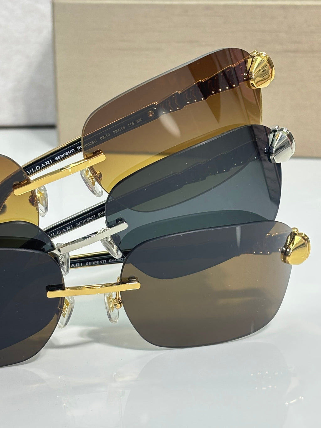 Stacked sunglasses with teal and dark lenses, gold metal frames on display.
