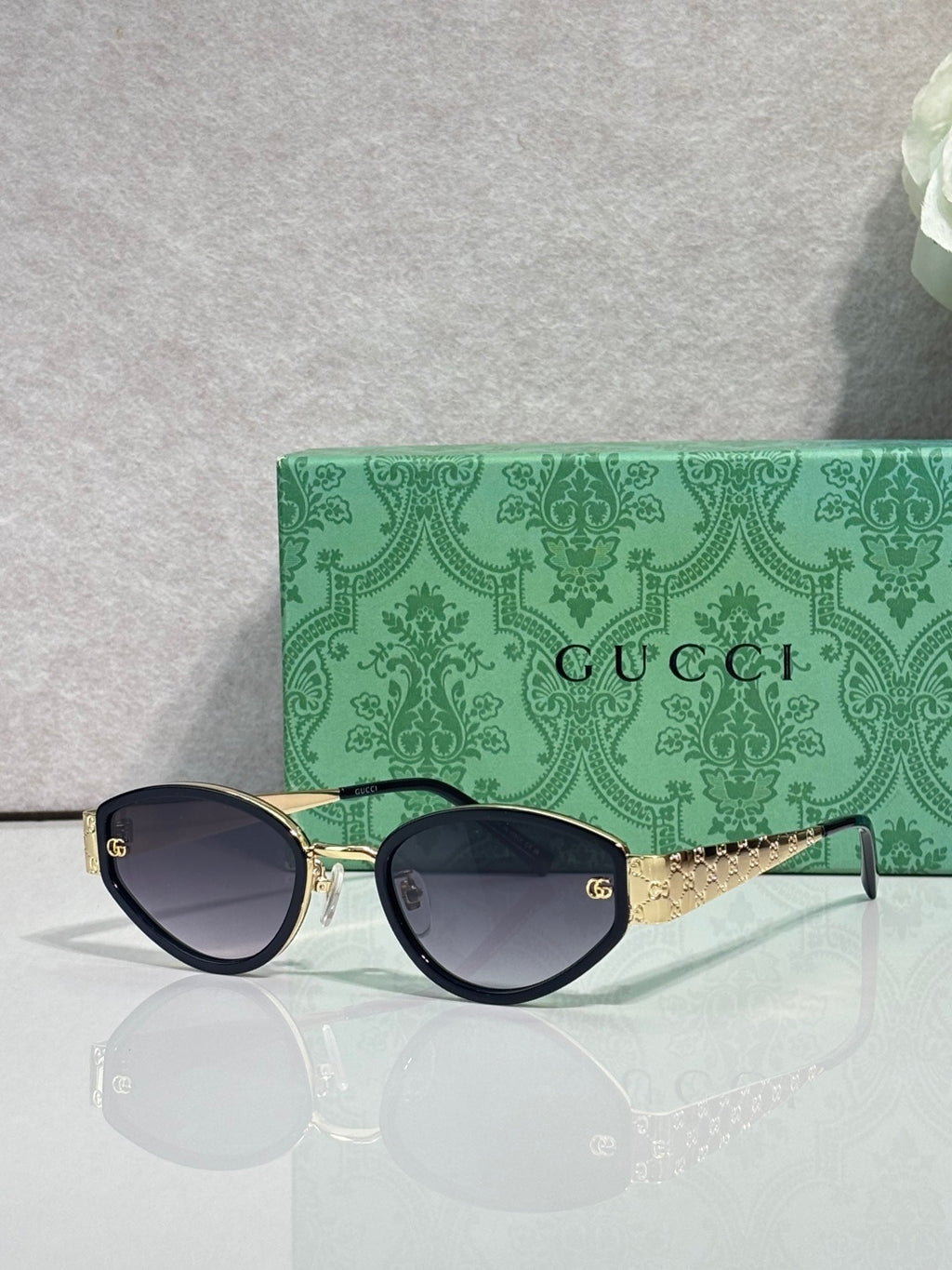 Cat-eye sunglasses with dark frames and gold-tone chain detail on temple