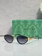 Cat-eye sunglasses with dark frames and gold-tone chain detail on temple