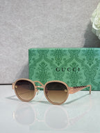 Gucci round sunglasses with tan lenses and light gold frame, decorative arms