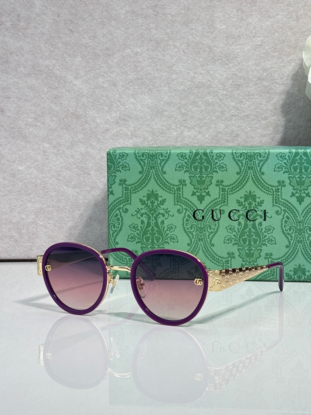 Gucci round sunglasses with purple lenses and dark frames, gold logo detail