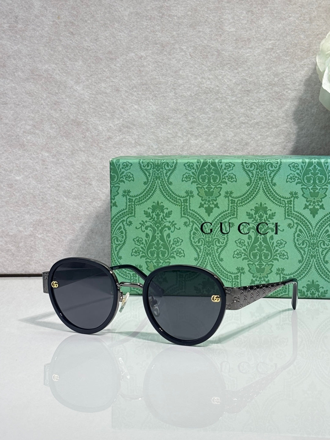 Gucci round sunglasses with dark lenses and black frames, gold logo on arms