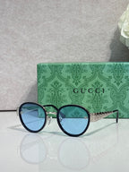 Gucci round sunglasses with dark blue lenses and black frames, gold logo detail