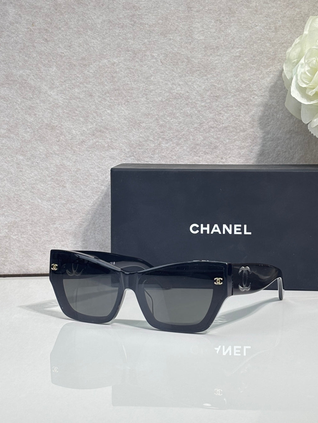 Eyeglasses with dark blue square frames and clear lenses, CHANEL logo on temples.