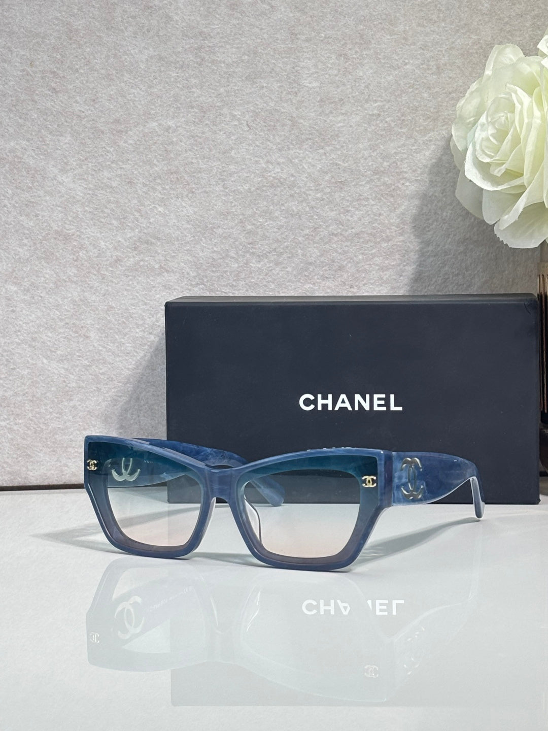 Eyeglasses with blue square frames and clear lenses, CHANEL logo on temples.