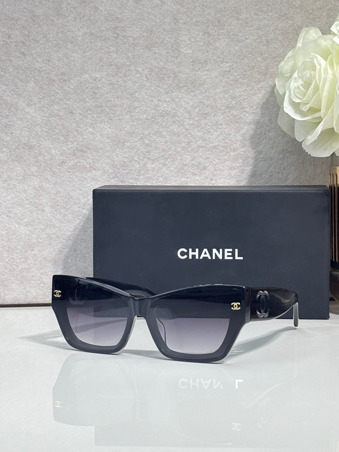 Eyeglasses with dark navy square frames and tinted lenses, CHANEL logo on temples.