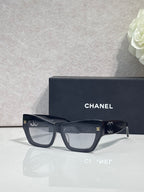 Eyeglasses with black square frames and tinted lenses, CHANEL logo on temples.