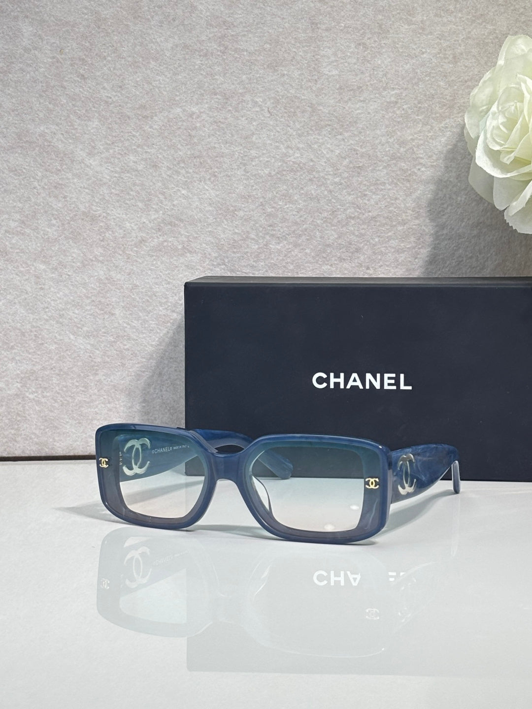 Blue-green square-frame glasses with logo detail and tinted lenses