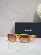 Tan square-frame glasses with logo hardware and tinted lenses