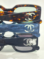 Layered CC-logo glasses with tortoiseshell and blue frames, tinted lenses