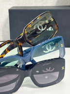 Stacked tinted glasses with CC logo fronts in blue and tortoiseshell frames