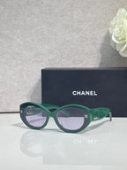 Green round-frame Chanel eyeglasses with logo temple detail and dark lenses.