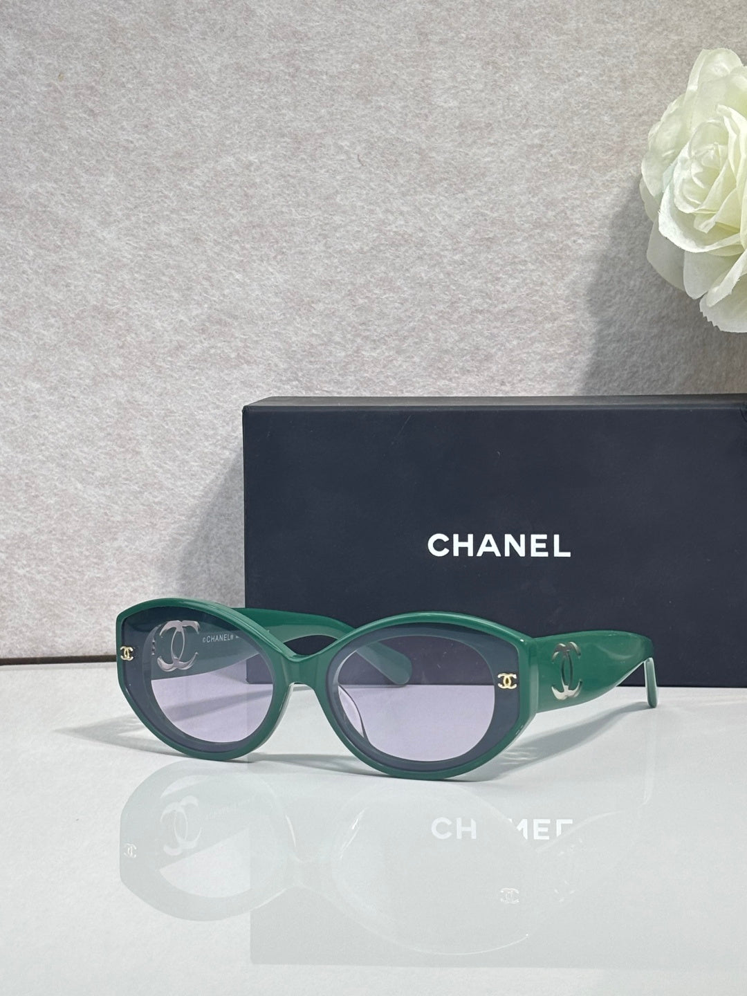 Green round-frame Chanel eyeglasses with logo temple detail and dark lenses.