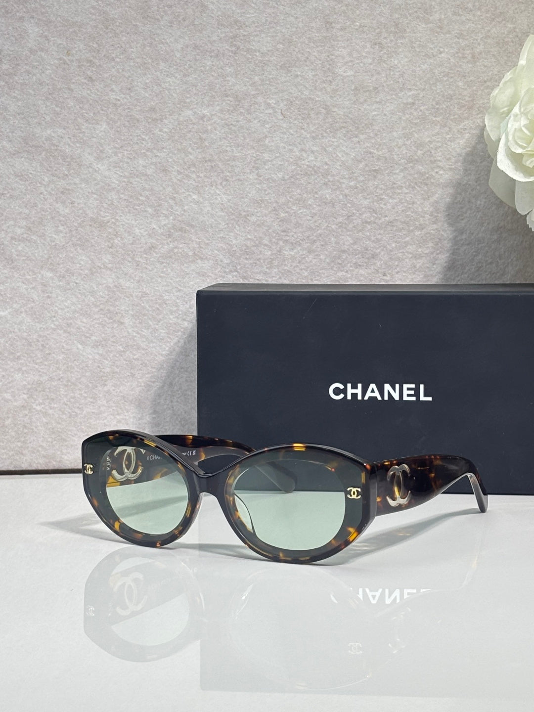 Dark tortoise round-frame Chanel eyeglasses with logo temples and tinted lenses.