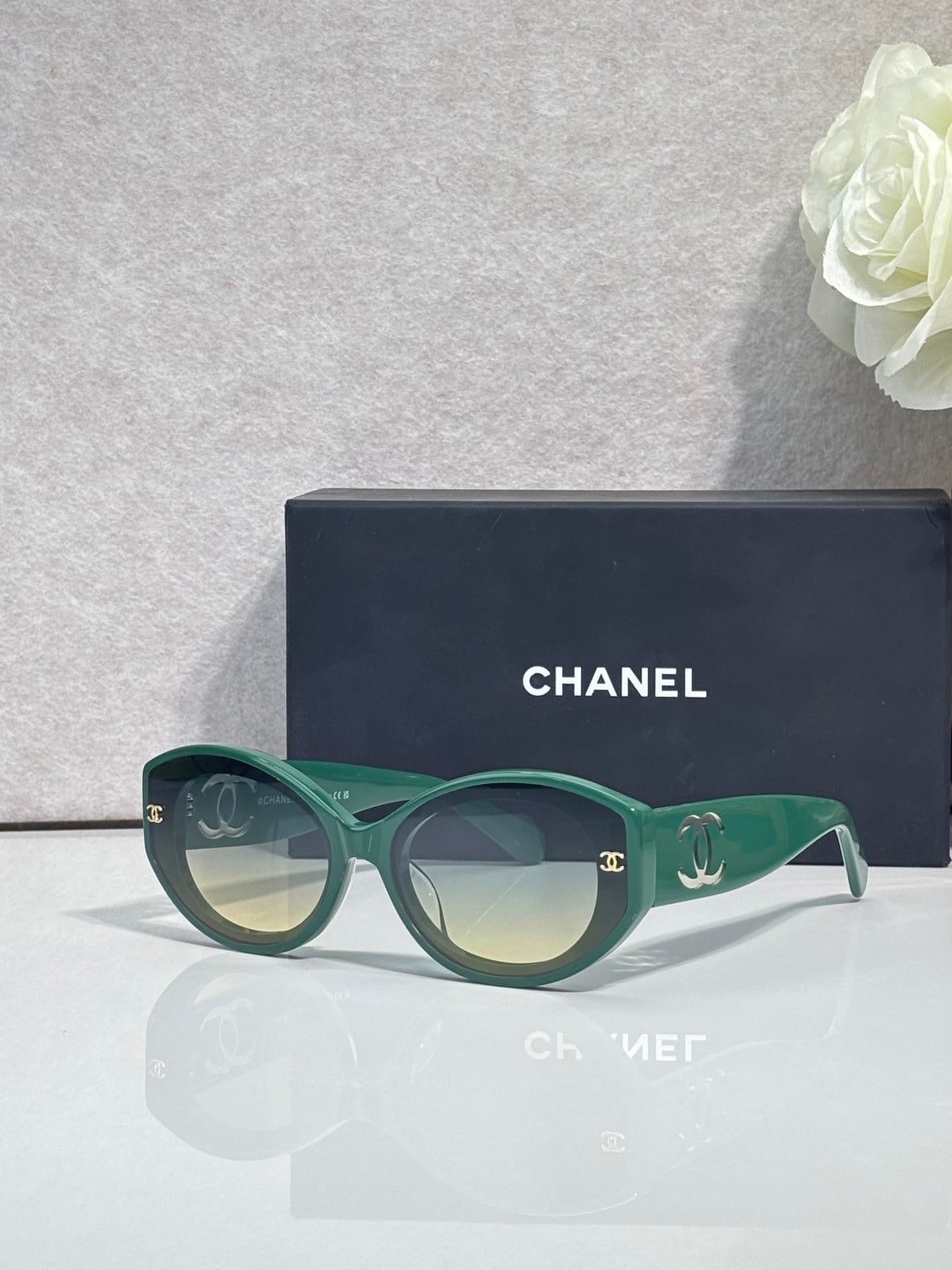 Green round-frame Chanel eyeglasses with logo temples and clear lenses.