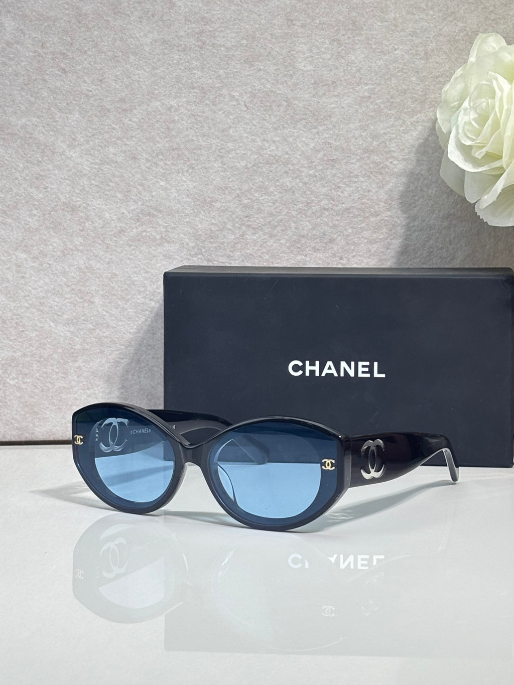 Black round-frame Chanel eyeglasses with logo temples and dark tinted lenses.