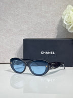 Black round-frame Chanel eyeglasses with logo temples and dark tinted lenses.