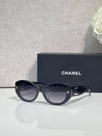 Black round-frame Chanel eyeglasses with logo temples and tinted lenses.