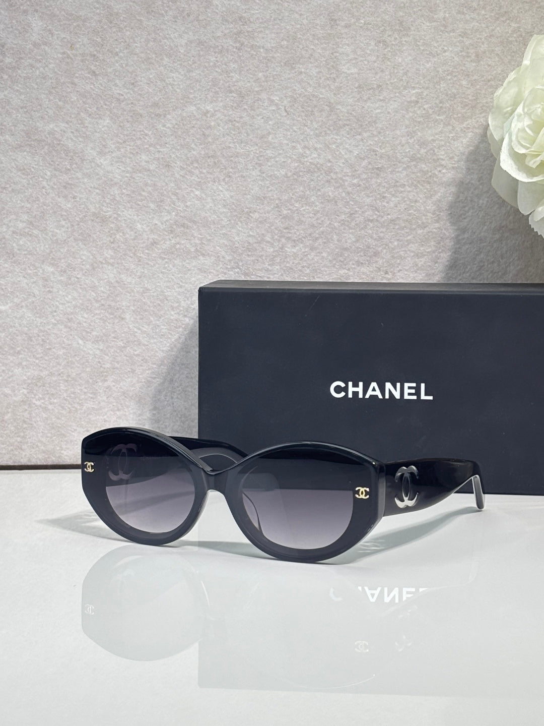 Black round-frame Chanel eyeglasses with logo temples and tinted lenses.