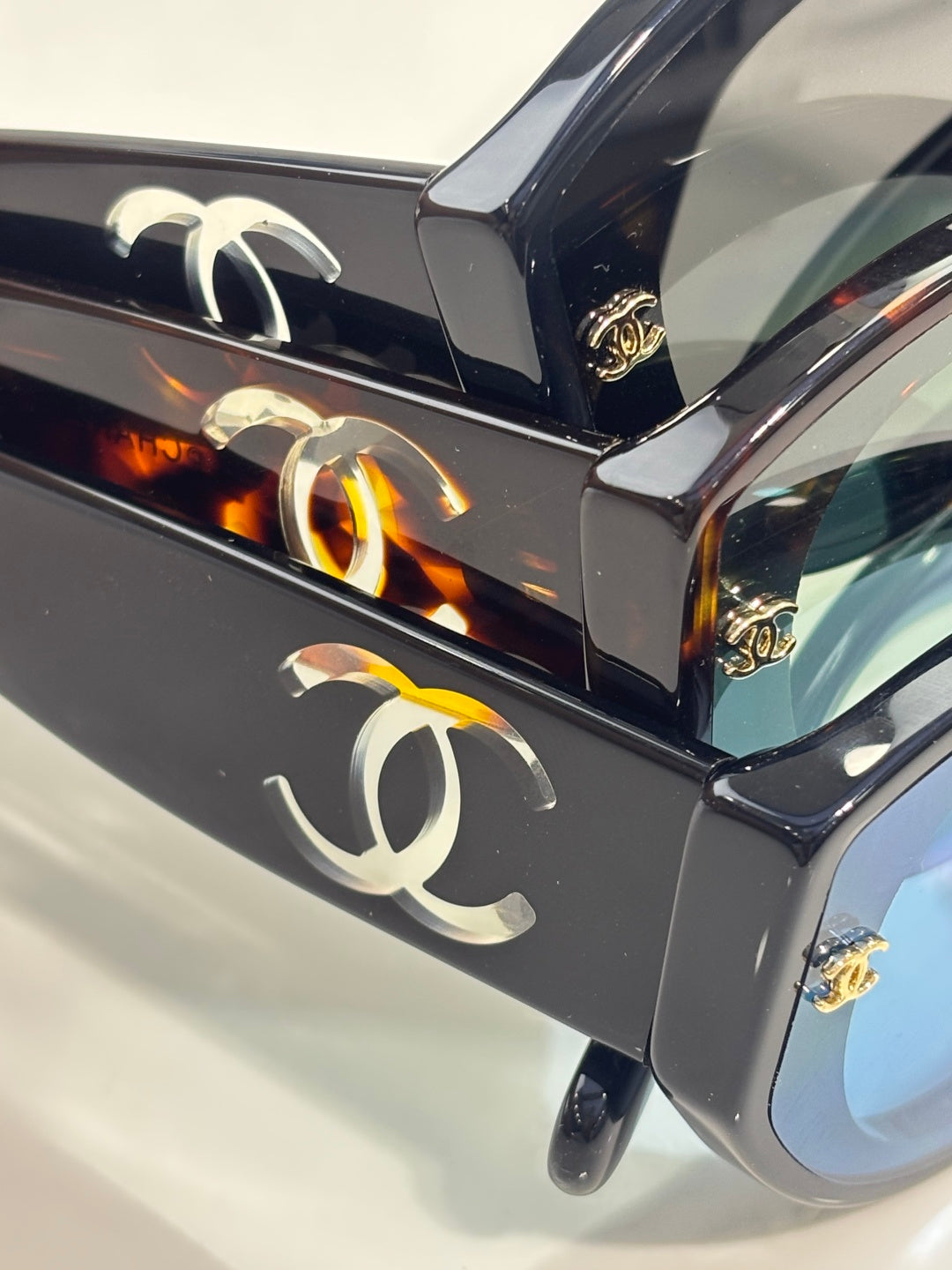 Chanel eyeglasses frame close-up with CC emblem and glossy black finish.