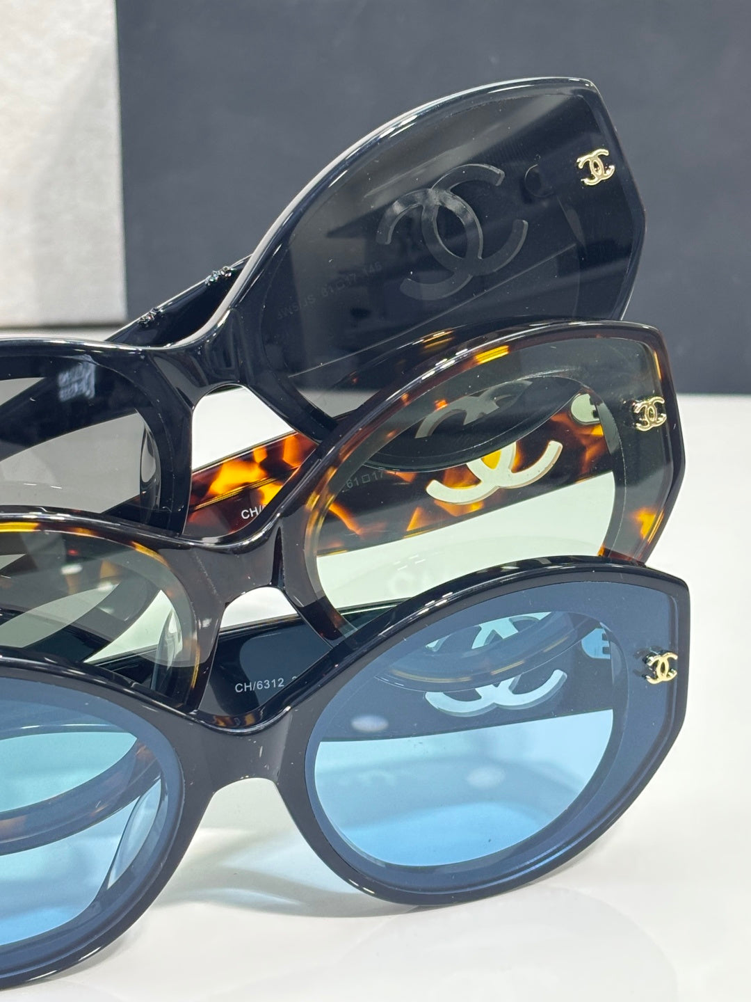 Chanel eyeglasses frame close-up with CC emblems and tortoise/blue lenses.