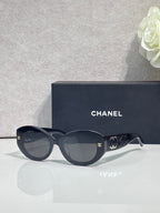 Black round-frame Chanel eyeglasses with logo temples and dark lenses.