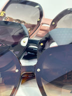 Chanel sunglasses, close-up of dark and pink frames with gold studs and logo hardware