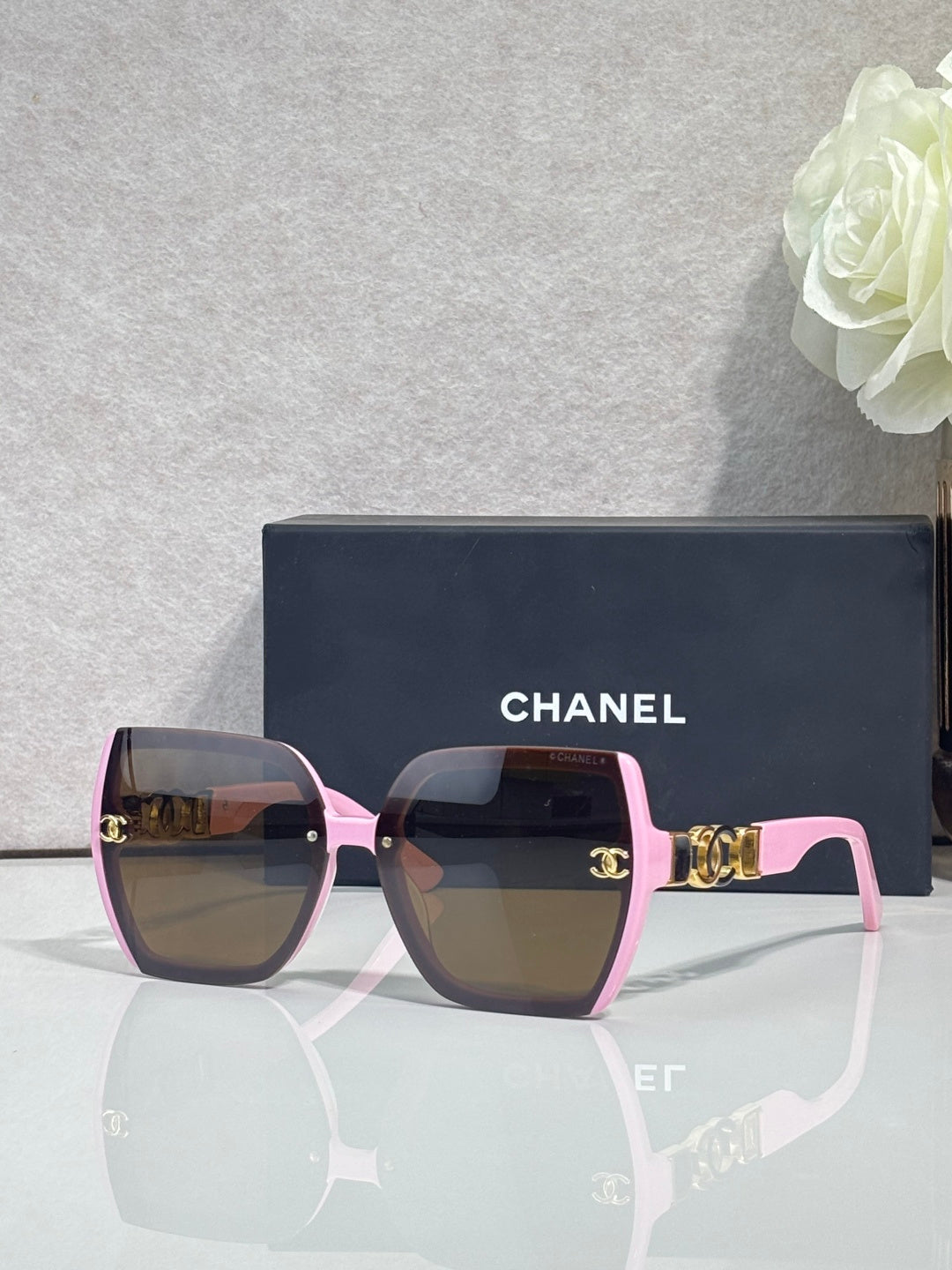 Chanel sunglasses with pink square frames, dark lenses, and gold temple details