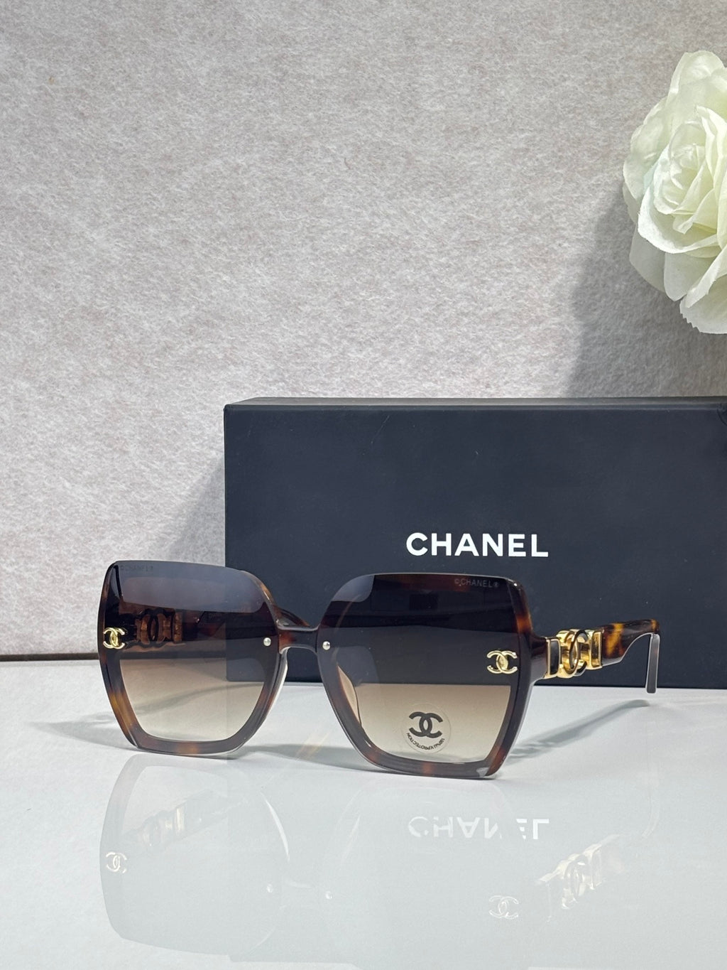 Chanel sunglasses with dark tortoise square frames, dark lenses, and gold temple hardware