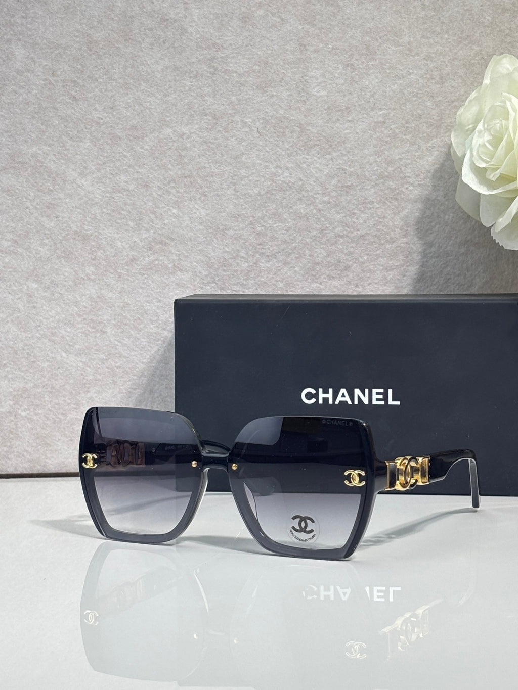 Chanel sunglasses with dark blue square frames, dark lenses, and gold temple hardware