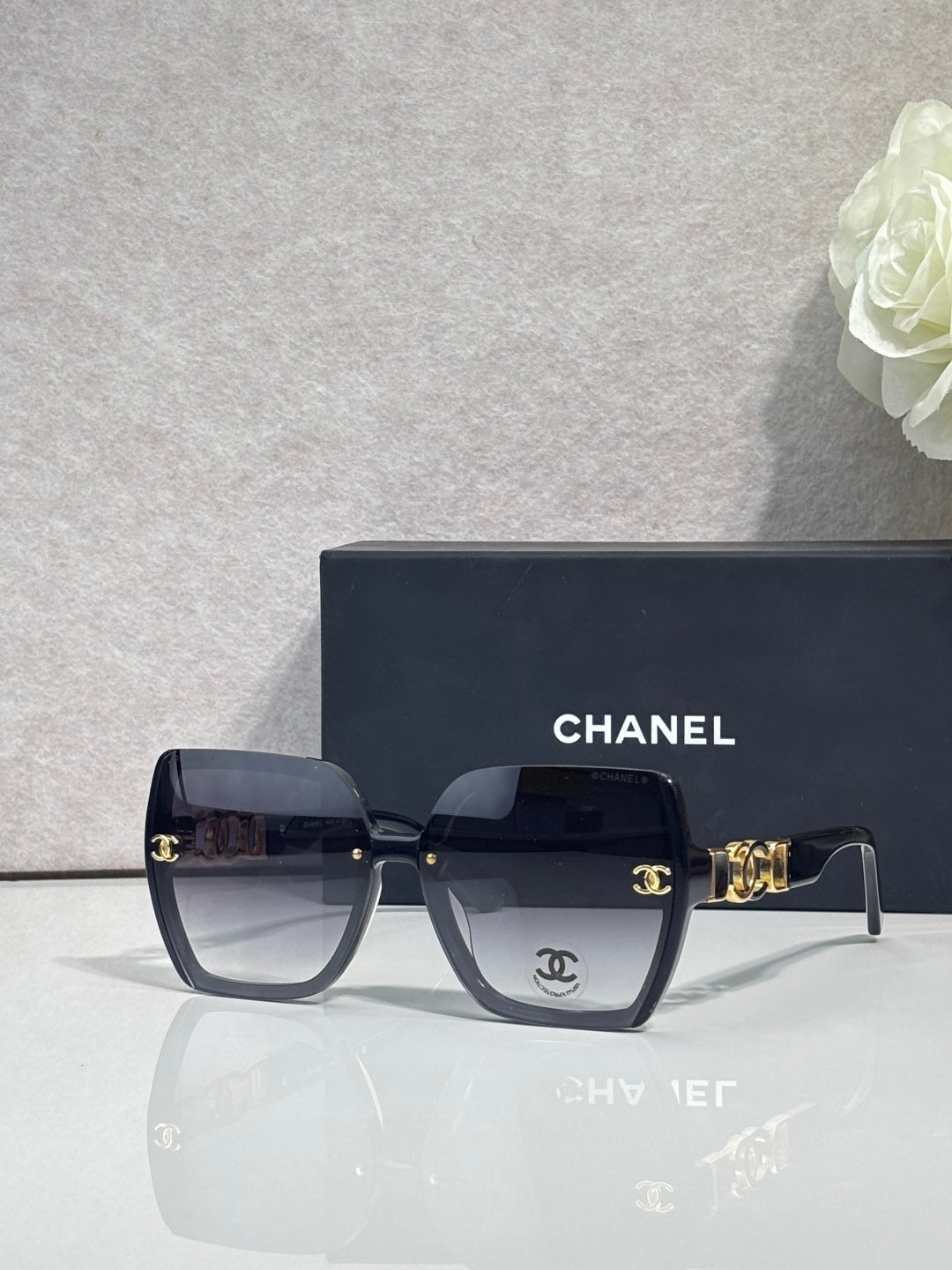 Chanel sunglasses with dark blue square frames, dark lenses, and gold temple hardware