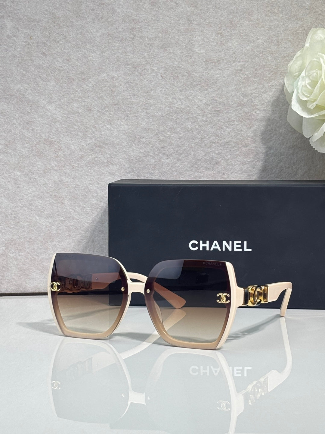 Chanel sunglasses with light pink square frames and dark lenses, gold temple detail