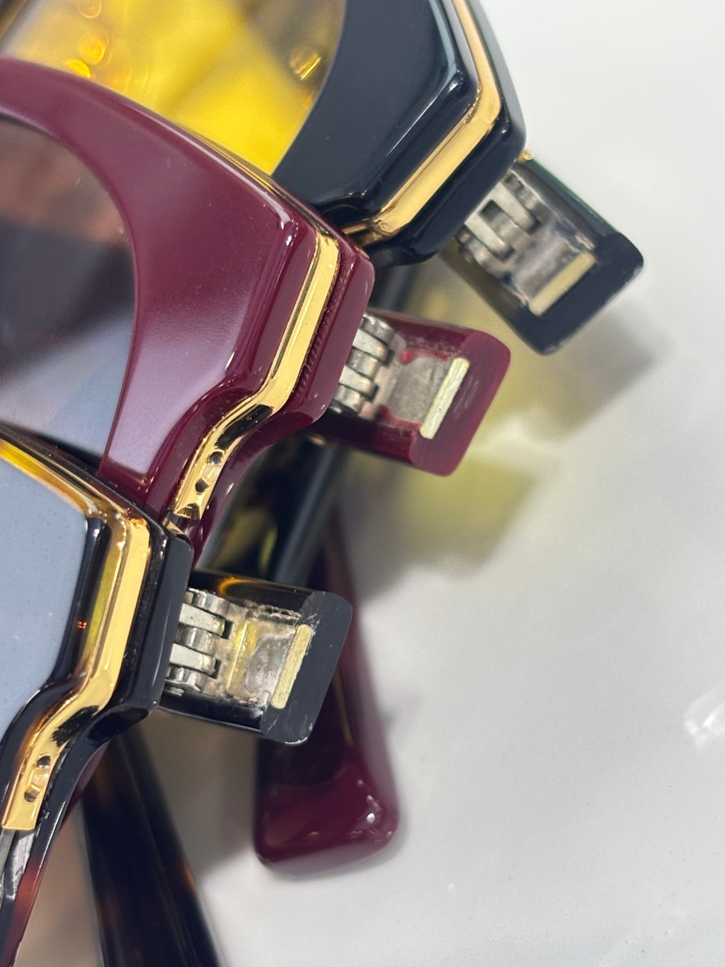 Gucci glasses hinge detail with gold hardware on burgundy and black frames