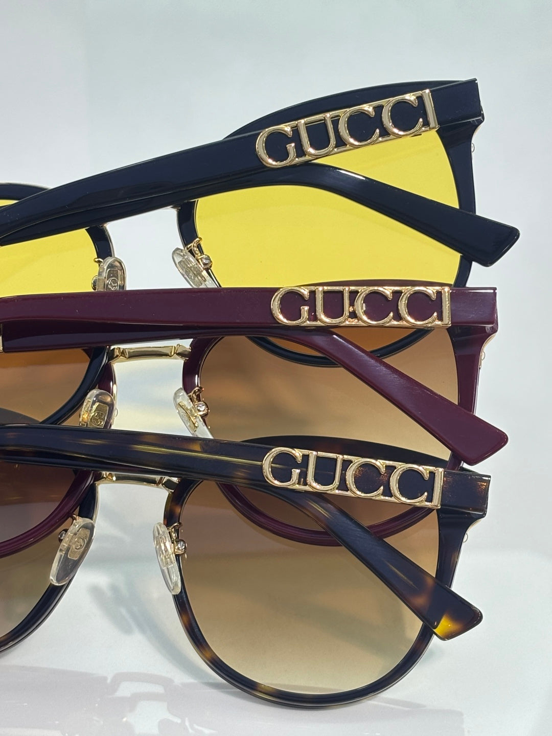Gucci glasses with navy frames, gold logo lettering on temples, and yellow lens panels
