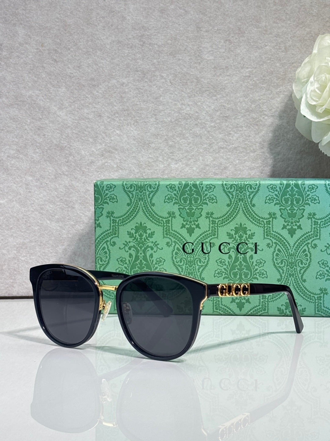 Gucci glasses with black square frames, gold hinges, and dark gradient lenses