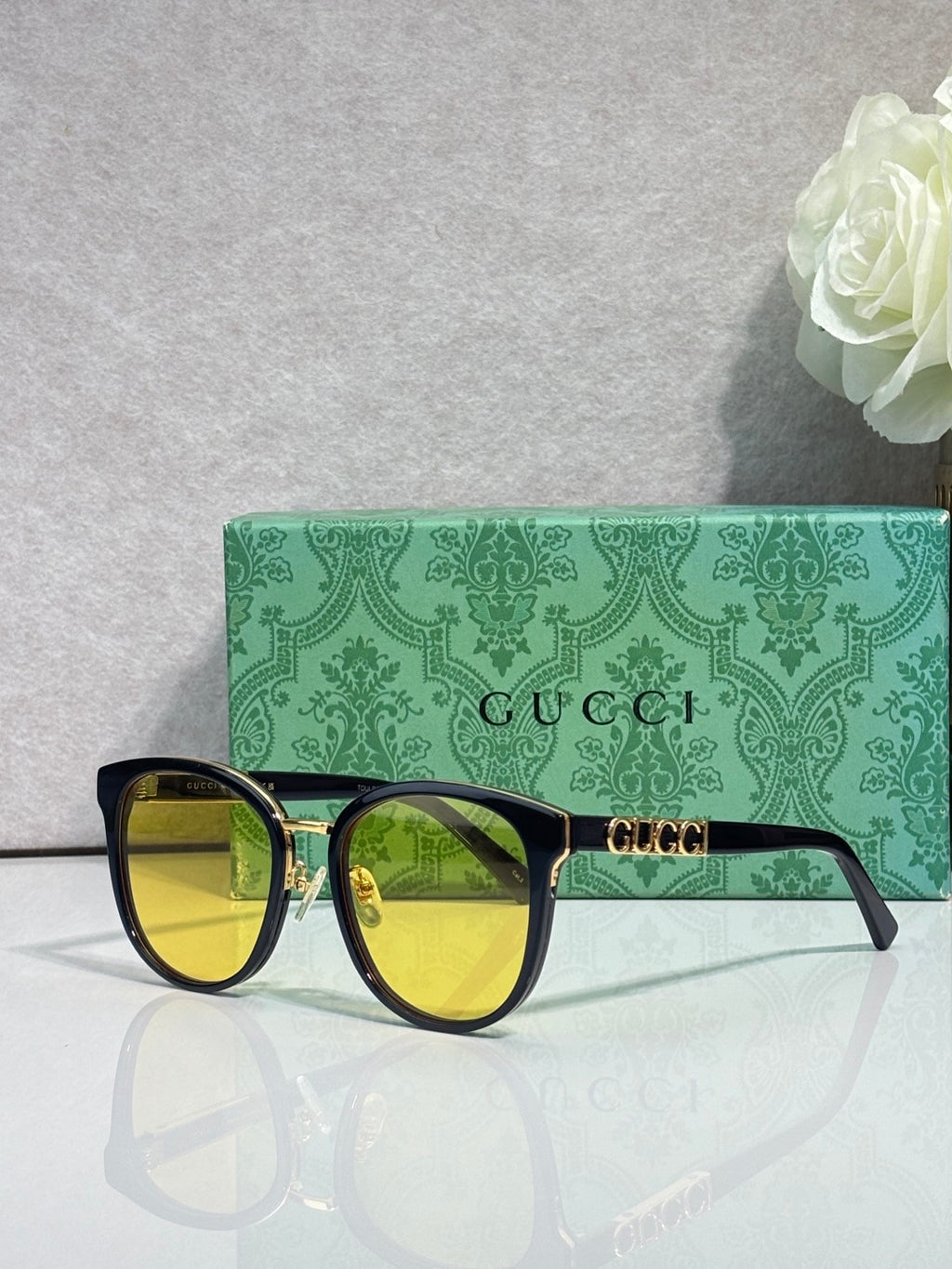 Gucci glasses with black square frames, gold accents, and yellow tinted lenses