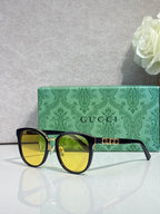 Gucci glasses with black square frames, gold accents, and yellow tinted lenses