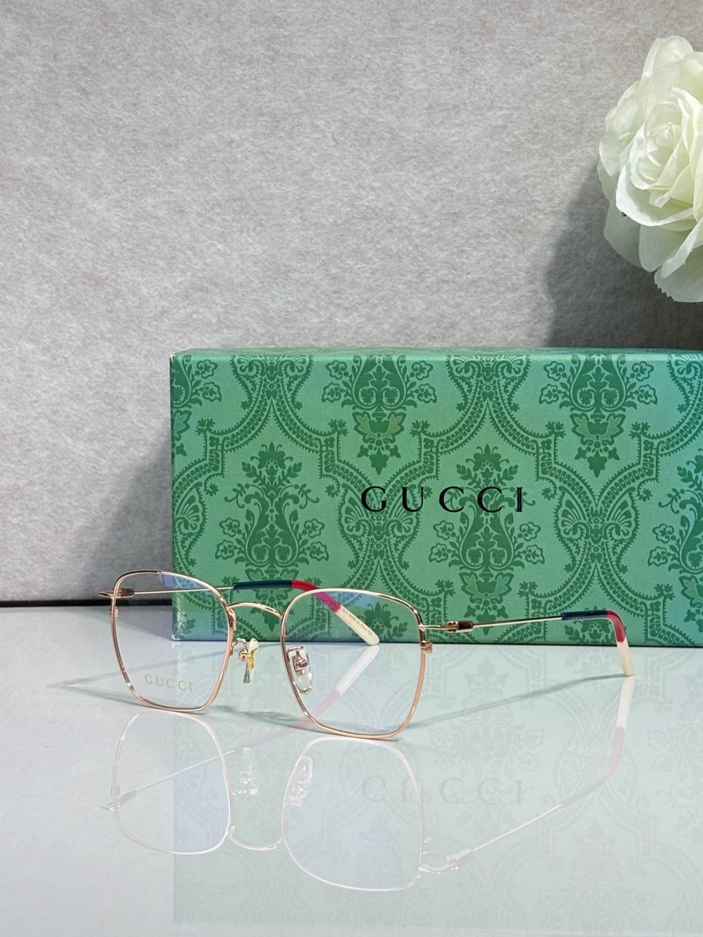 Gucci optical glasses with green frame, gold details, red accent arm, clear lenses