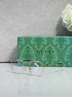 Gucci optical glasses with green frame, gold details, red accent arm, clear lenses