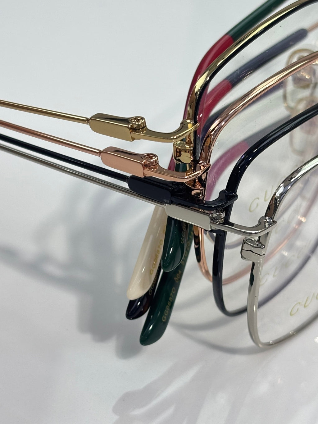 Gucci optical glasses close-up: gold connector with green and red striped temple